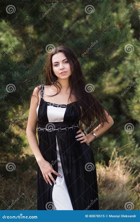 Graceful Charming Brunette Model Posing In Black Dress In Coniferous