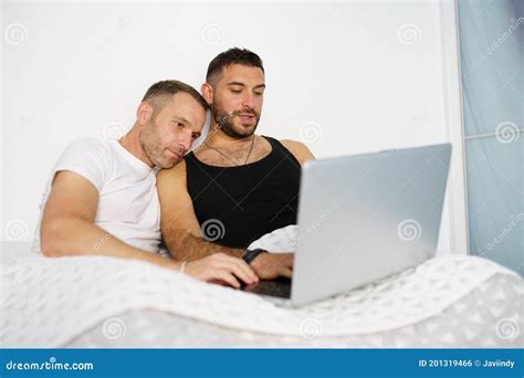 Gay Couple Consulting Something On Their Laptop While Lying On The Bed Stock Photo Image Of