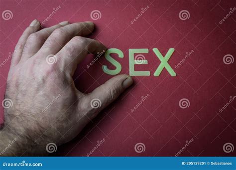 Human Fingers Holding The Word Sex Written With Plastic Letters On Dark