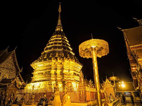 people standing in front of a golden pagoda at night