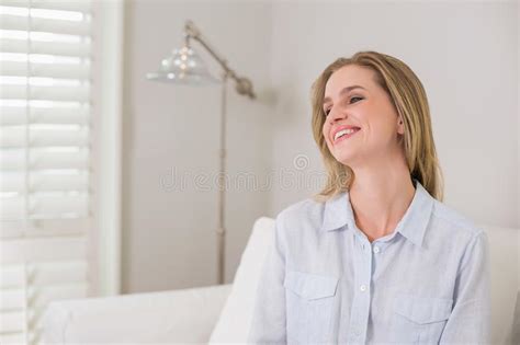 Casual Laughing Blonde Sitting On Couch Looking Away Stock Image