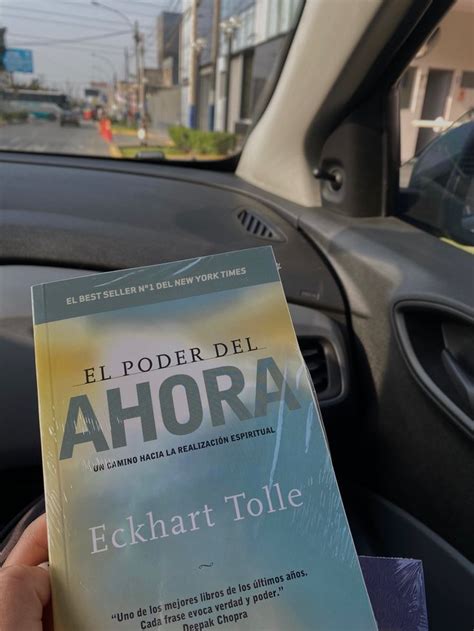 A Person Is Holding Up A Book In Their Hand While Driving Through The