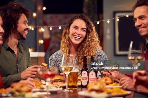 Multicultural Group Of Friends Enjoying Night Out Eating Meal And