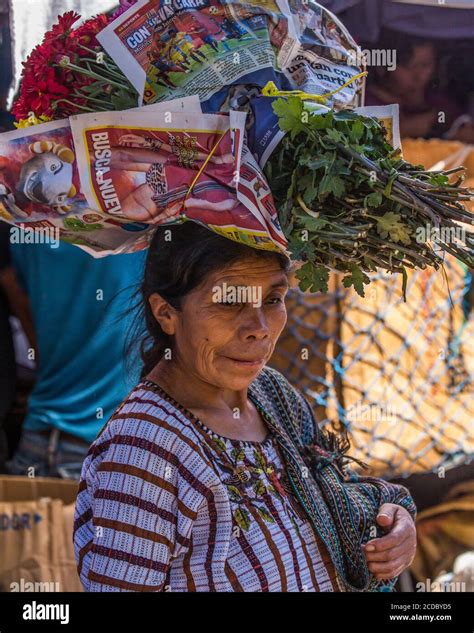 An Older Tzutujil Mayan Woman In Traditional Dress Balances A Load Of