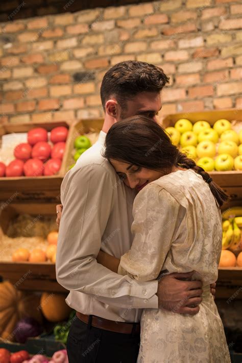 Homme Embrassant Une Femme Joyeuse Près De Boîtes De Fruits Photo