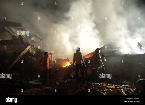 People Gather In Front Of Burning Wreckage Of Plane At The Site Of