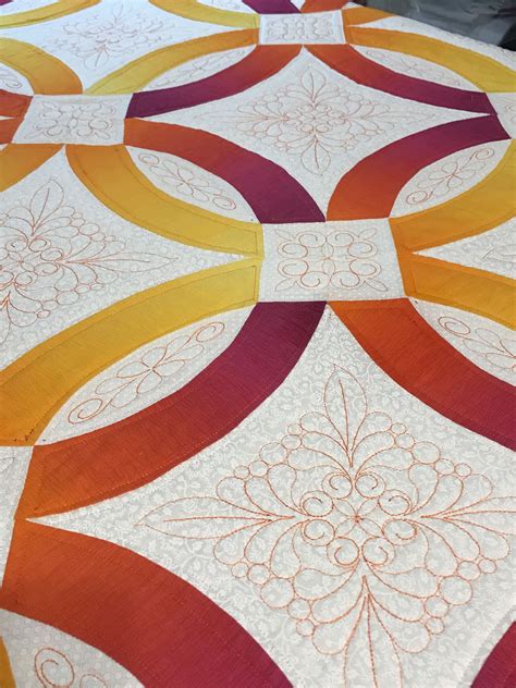 An Orange Yellow And Red Quilt Is Laying On Top Of A Tablecloth That