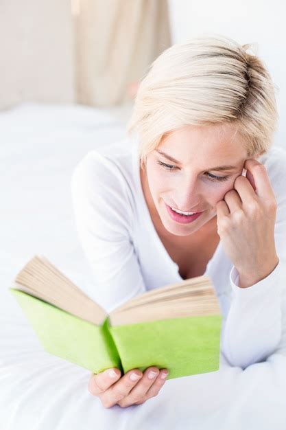 Premium Photo Smiling Blonde Woman Lying On The Bed And Reading A Book