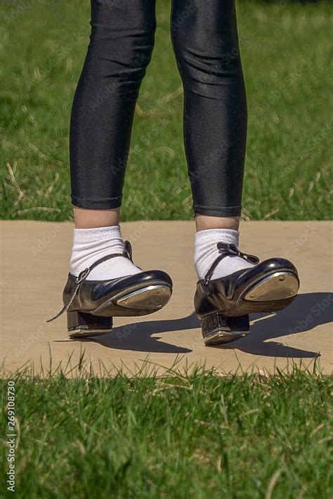 Legs And Feet Of Young Girl In Black Tap Shoes White Socks And Black