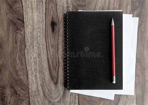 Cuaderno Espiral Y Pluma Negros En La Tabla De Madera Imagen De Archivo