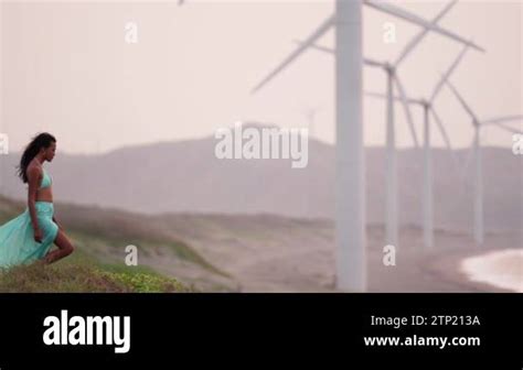 A Woman In A Bikini Walks In Slow Motion And Marvels At The Rows Of Wind Turbines On The Beach
