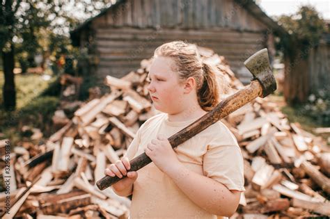 Beautiful Chubby Girl Stands With An Axe Against The Background Of A