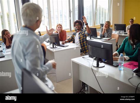 Teacher In Classroom Giving Word To Gay With Raised Hand Stock Photo Alamy