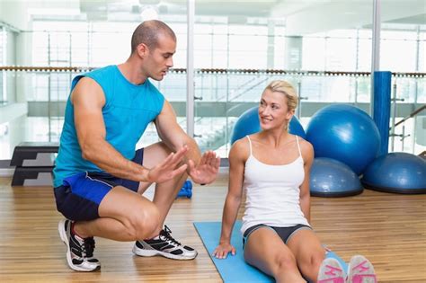 Premium Photo Trainer Assisting Woman With Exercises At Fitness Studio