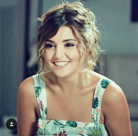 A Woman Smiling And Sitting Down With Her Hair In A Messy Updo Wearing