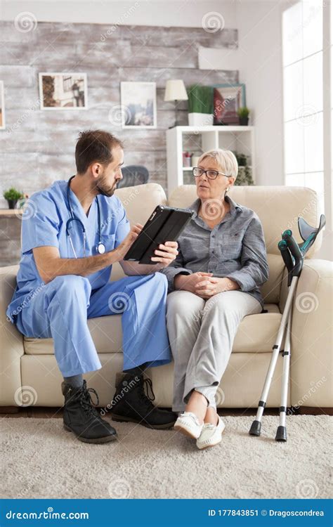 Old Woman With Crutches In Nursing Home Sitting On Couch Stock Image
