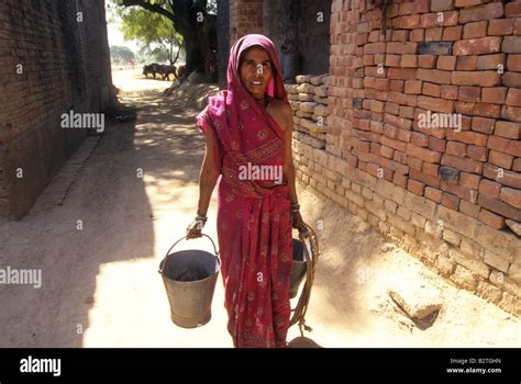 A Woman Carries Water Buckets Through A Village In Uttar Pradesh