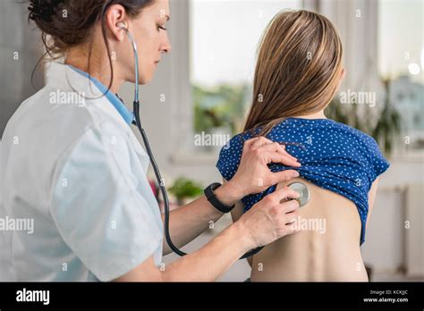 Doctor Listening To Patients Chest With Stethoscope In His Office At