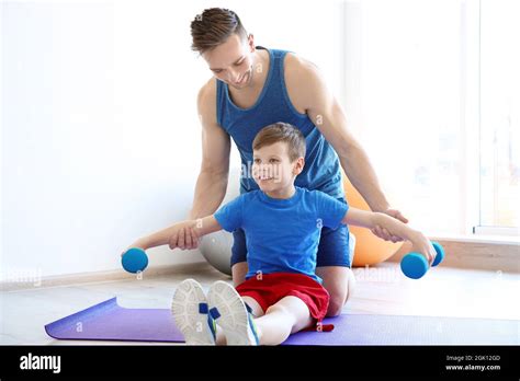 Papa et son fils font des exercices avec des haltères sur tapis dans la