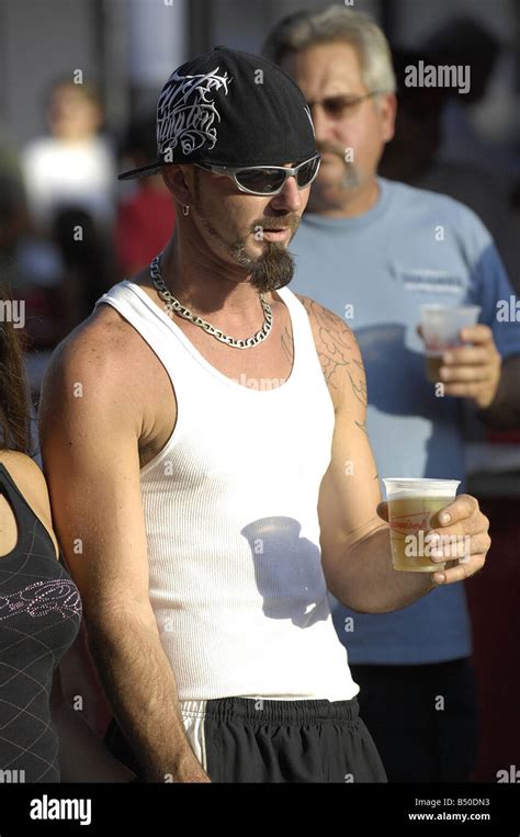 A Man With Sunglasses And Backwards Cap Sporting An Interesting Beard