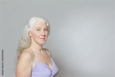 Headshot Of A Mature Woman With Freckles And Shiny Long Gray Hair In Front Of White Background