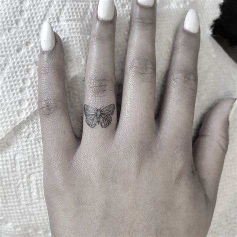 Butterfly tattoo on the ring finger.