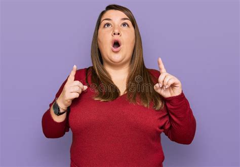 Beautiful Brunette Plus Size Woman Wearing Casual Clothes Amazed And Surprised Looking Up And