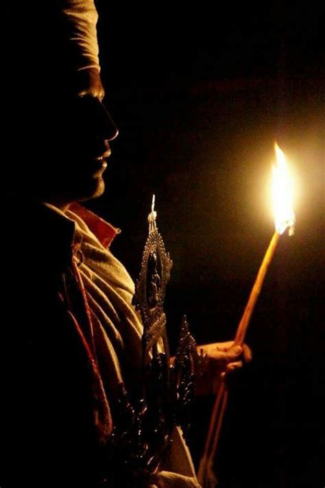 A Man Holding A Lit Candle In His Hand