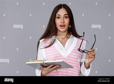 Surprised Beautiful Brunette Woman With Glasses And Book On Grey