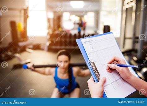 Woman Exercising In Gym Personal Trainer Plan On Clipboard Stock