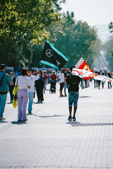 People With Formula 1 Flags In Sunlit Park In City · Free Stock Photo