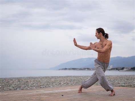 Caucasian Man With Naked Torso Practicing Wushu On The Seashore Stock