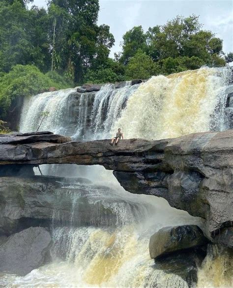 Two People Are Standing At The Edge Of A Waterfall While Another Person