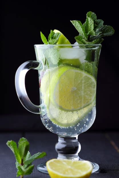 Refrescante mojito frío en un vaso alto con hielo menta limón y lima