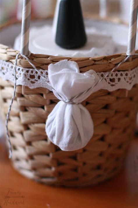 A Wicker Basket With Candles And Napkins Tied To The Handle Sitting On A Table