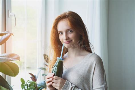 Young Smiling Woman Holding Glass Bottle Of Green Healthy Smoothie