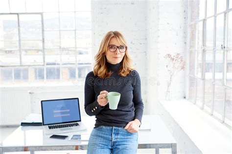 Beautiful Businesswoman Standing In The Office While Drinking Her