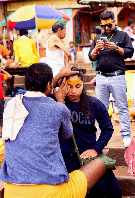 A Priest Applying Sandalwood Paste On The Forehead Of A Woman Devotee