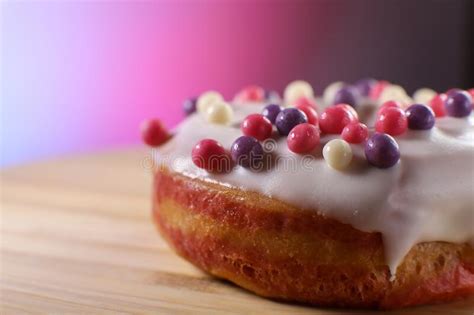 White Icing Donut With Small Colored Pieces Of Chocolate On A Wooden