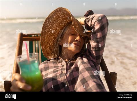 Senior Woman Having Cocktail Drink While Relaxing On Sun Lounger At