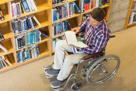 Hombre En Silla De Ruedas Leyendo Un Libro En La Biblioteca Foto Premium