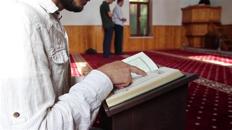 joven hombre leyendo el Corán en pie en un mesa en el mezquita el