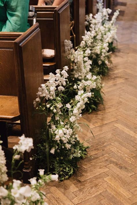 White Flowers Are Lined Up Along The Side Of Pews