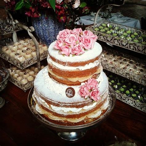 A Three Tiered Cake With Pink Flowers On Top And Other Desserts In The