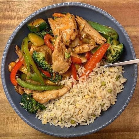 A Blue Bowl Filled With Rice Chicken And Veggies