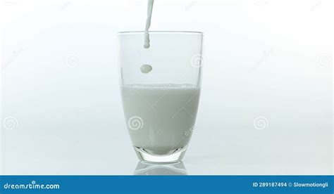 Milk Being Poured Into Glass Against White Background Stock Photo