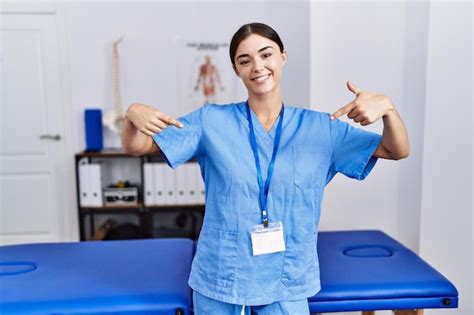 Premium Photo Young Hispanic Woman Wearing Physiotherapist Uniform Standing At Clinic Looking