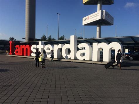 two people walking past a large sign that says i am amsterdam in front ...