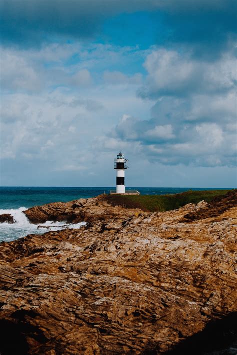 Lighthouse on Rocky Island during Day · Free Stock Photo