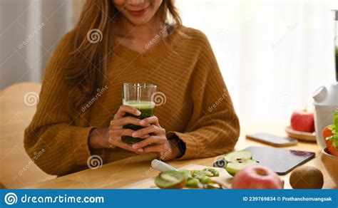 Smiling Woman Holding Glass Of Healthy Green Vegetable Smoothie In Her